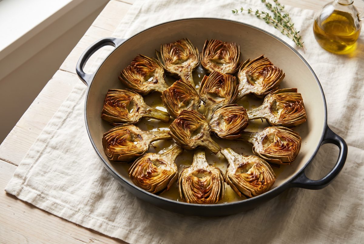 Halved artichoke hearts browned deep gold in a wide pan