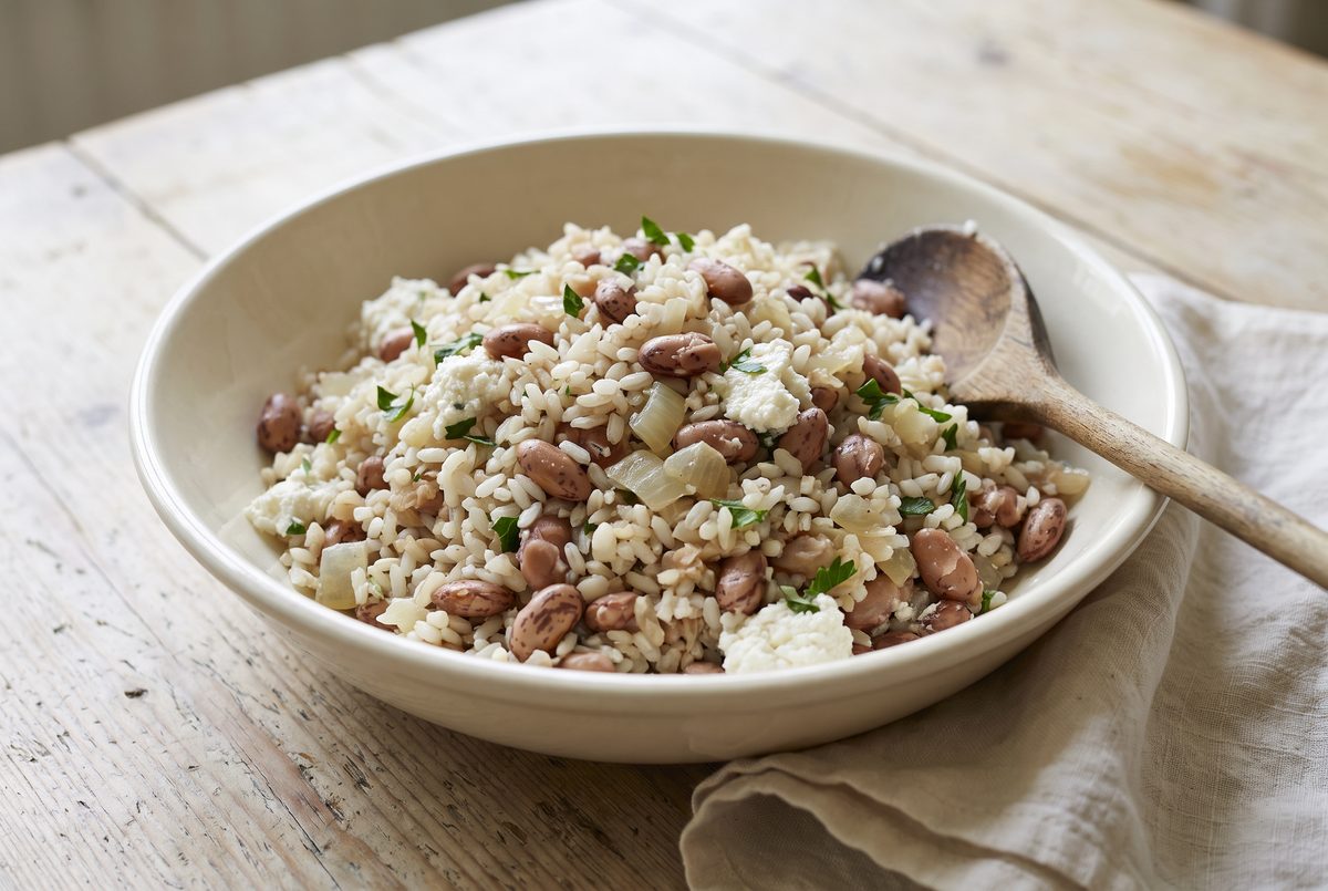Pale filling of rice, crushed borlotti beans, ricotta and parsley just combined in a cream ceramic bowl, spoon resting on the rim