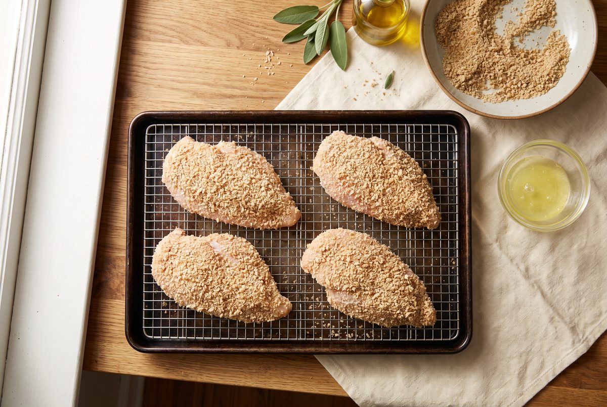 Breaded chicken breasts on a wire rack, ready for the oven